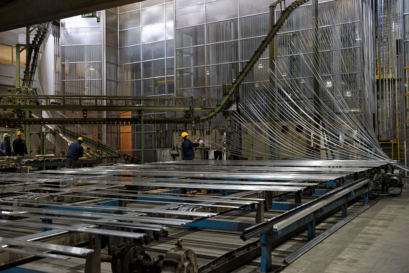 Aluminum profiles moving on an overhead conveyor through a powder coating line
