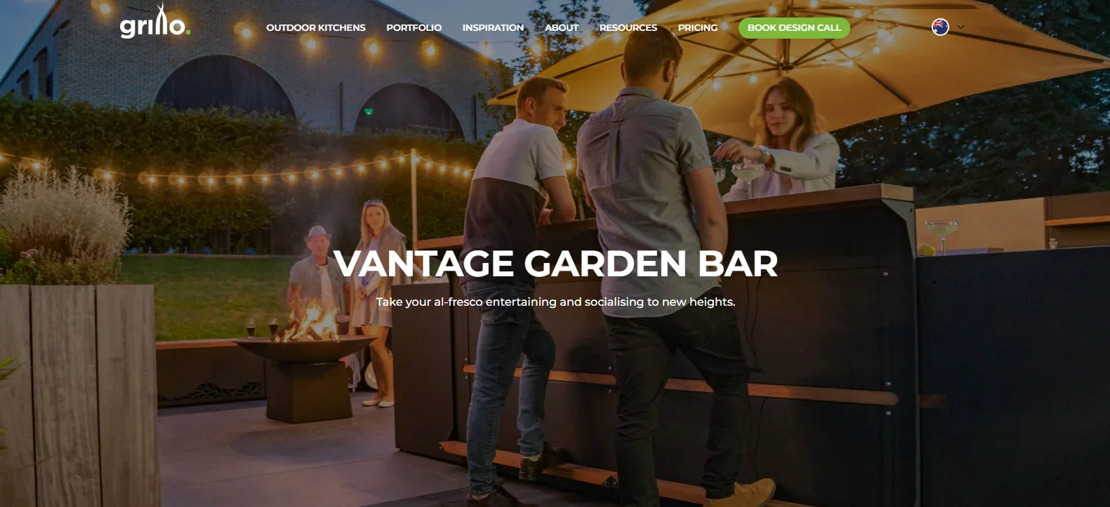 Grillo Outdoor Kitchens homepage hero headed Vantage Garden Bar, with guests at a timber-framed garden bar under string lights beside a fire pit