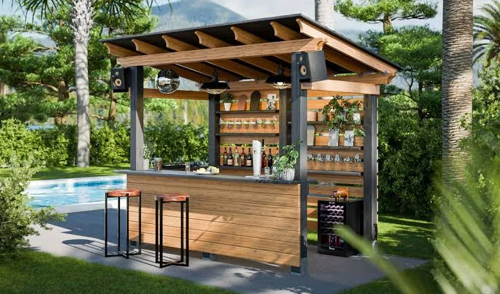 Timber-framed garden bar with a tiled roof, bottle shelf, bar stools and a wine rack beside a swimming pool and palm trees, illustrating how to shortlist patio bar manufacturers Australia