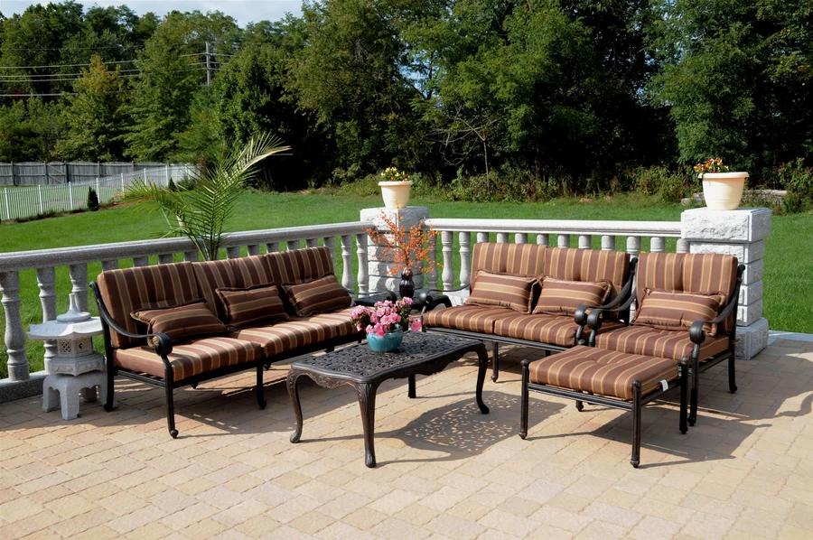 Ornate cast aluminum dining set with lattice-back chairs and a patterned table on a flagstone patio