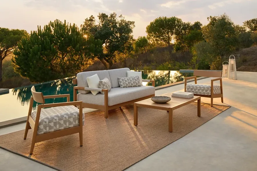 Acacia hardwood lounge set with a coffee table beside an infinity pool at sunset