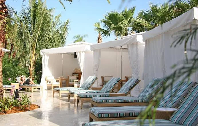 Resort pool deck cabana with loungers and side tables